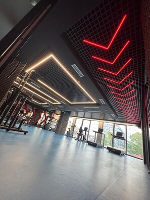 Un gimnasio con equipamiento de ejercicio y amplias ventanas.
