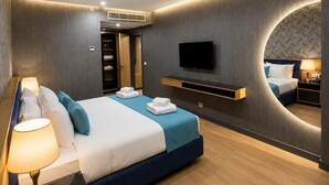 Una habitación de hotel moderna con cama, mesita de noche, lámpara y televisor montado.