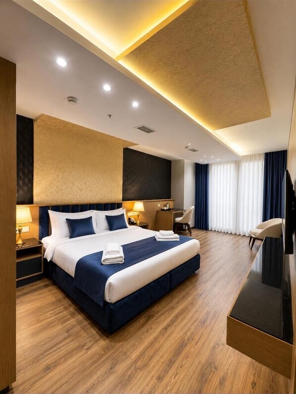 Una habitación de hotel moderna con una cama grande, mesitas de noche, un escritorio y un televisor de pantalla plana.