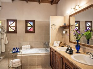 Ein Badezimmer mit einer Badewanne, zwei Waschbecken, einem großen Spiegel und einem Handtuchhalter.