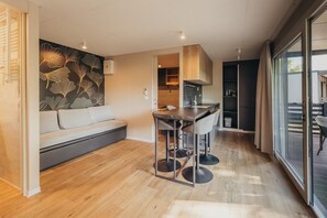 A modern kitchen with a black countertop, a wooden cabinet, and a built-in oven. - Luxury Forest Retreat with Pool Access (Karlovac)
