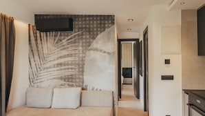 Un dormitorio moderno con una cama grande, un televisor montado en la pared y un pasillo que conduce a una cocina.