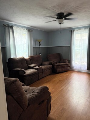 A living room with a ceiling fan, a sofa set, and a lamp.