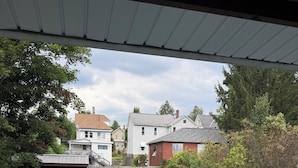 Une terrasse en bois avec un banc, une cour clôturée et des maisons en arrière-plan.