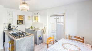 A compact kitchen with a gas stove, sink, and a small dining area with a table and chairs.