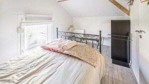 A bedroom with a bed, a window, a door, and a wardrobe.