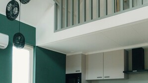 A modern kitchen with white cabinets, a wooden dining table, and a staircase leading to an upper level. - The bungalow Palthe Comfort offers comfort and tranquility in nature for 4 people, with modern amenities and a lovely terrace. (Nieuw Heeten)