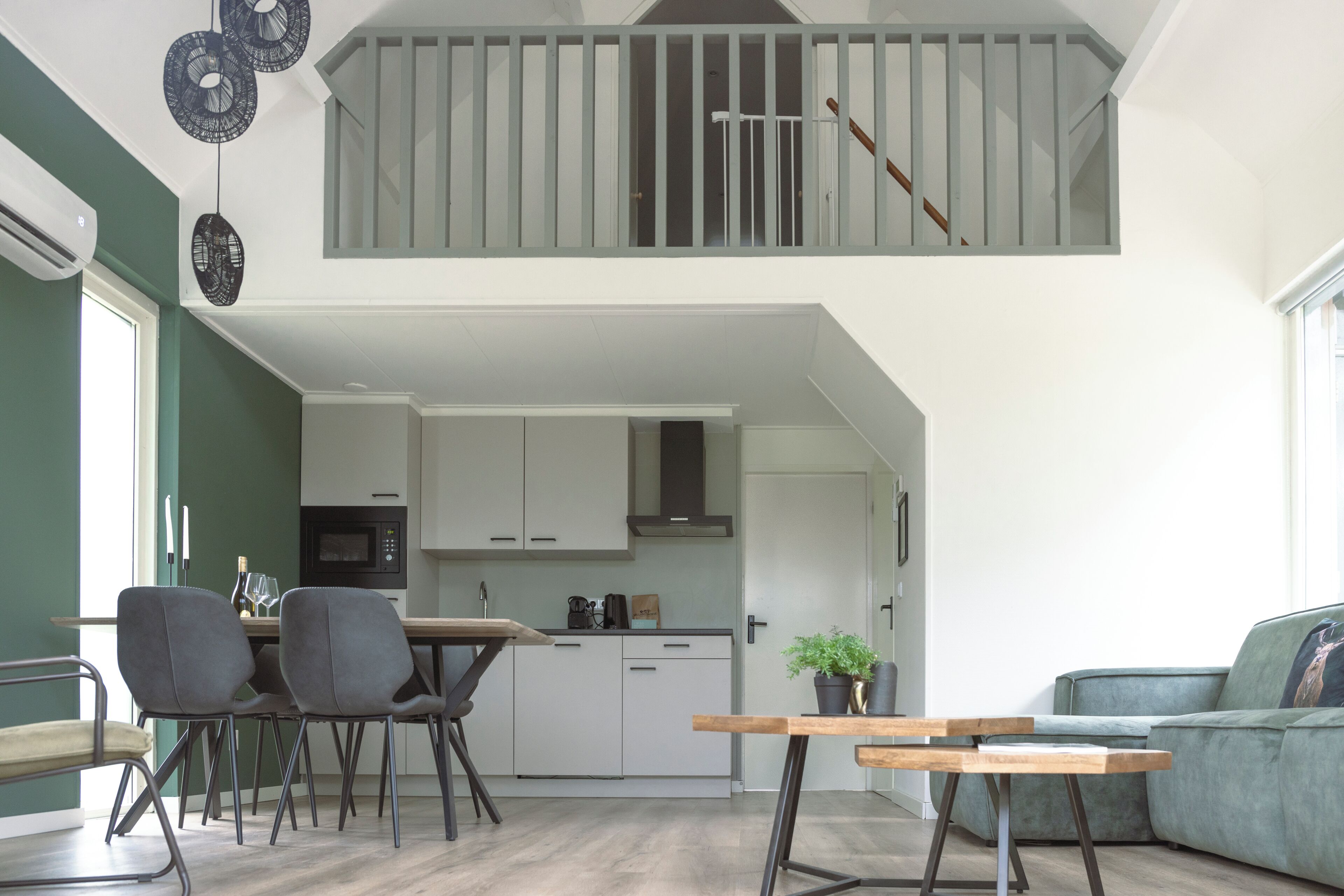 A modern kitchen with white cabinets, a dining area with a table and chairs, and a staircase leading to an upper level.