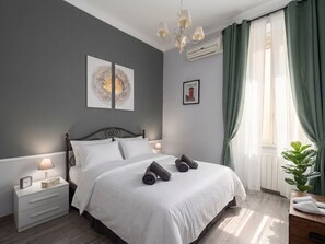 A bedroom with a bed, nightstand, lamp, artwork, and curtains. - Quiet Central Apartment (Roma)