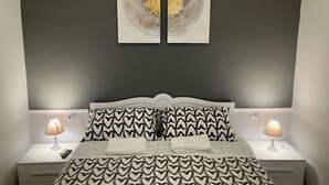 A bedroom with a bed, two nightstands, two lamps, and two wall-mounted artworks. - Quiet Central Apartment (Roma)