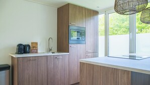 A modern kitchen with wooden cabinets, a built-in microwave, and a window providing a view of greenery. - The Palthe Premium Living bungalow has been recently fully renovated and features a stylish, modern interior. It offers all the comfort for 4 people, surrounded by nature, with a lovely terrace to relax outdoors. (Nieuw Heeten)