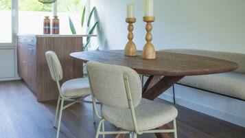 Een eetgedeelte met een ronde houten tafel, twee stoelen en twee houten kandelaars.