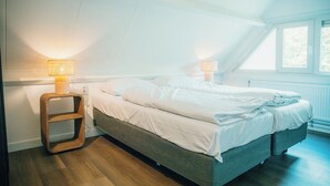 A bedroom with a bed, two bedside lamps, a wooden nightstand, and a window. - The Palthe Premium Living bungalow has been recently fully renovated and features a stylish, modern interior. It offers all the comfort for 4 people, surrounded by nature, with a lovely terrace to relax outdoors. (Nieuw Heeten)