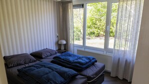 A room with a bed, a bedside table, a lamp, and a window with curtains. - The Palthe Premium bungalow has been recently fully renovated and features a stylish, modern interior. It offers all the comfort for 4 people, surrounded by nature, with a lovely terrace to relax outdoors. (Nieuw Heeten)