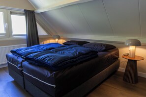 Une chambre à coucher avec un lit, une lampe de chevet et une fenêtre avec des rideaux.