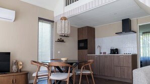 A modern kitchen with wooden cabinets, a dining table with chairs, a built-in microwave, and a coffee maker. - The Palthe Premium bungalow has been recently fully renovated and features a stylish, modern interior. It offers all the comfort for 4 people, surrounded by nature, with a lovely terrace to relax outdoors. (Nieuw Heeten)