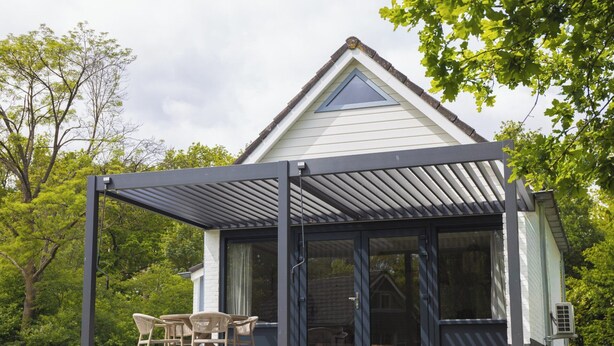 A house with a covered patio, a glass door entrance, and a lawn with chairs. - The Palthe Premium bungalow has been recently fully renovated and features a stylish, modern interior. It offers all the comfort for 4 people, surrounded by nature, with a lovely terrace to relax outdoors. (Nieuw Heeten)