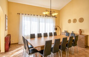 Ein Esszimmer mit Holztisch und -stühlen, einer Kristallleuchter und einem Fenster mit Vorhängen.