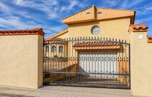 Ein verschlossenes Tor mit schmiedeeisernem Gitter, einem Ziegeldach und einem kleinen Fenster.