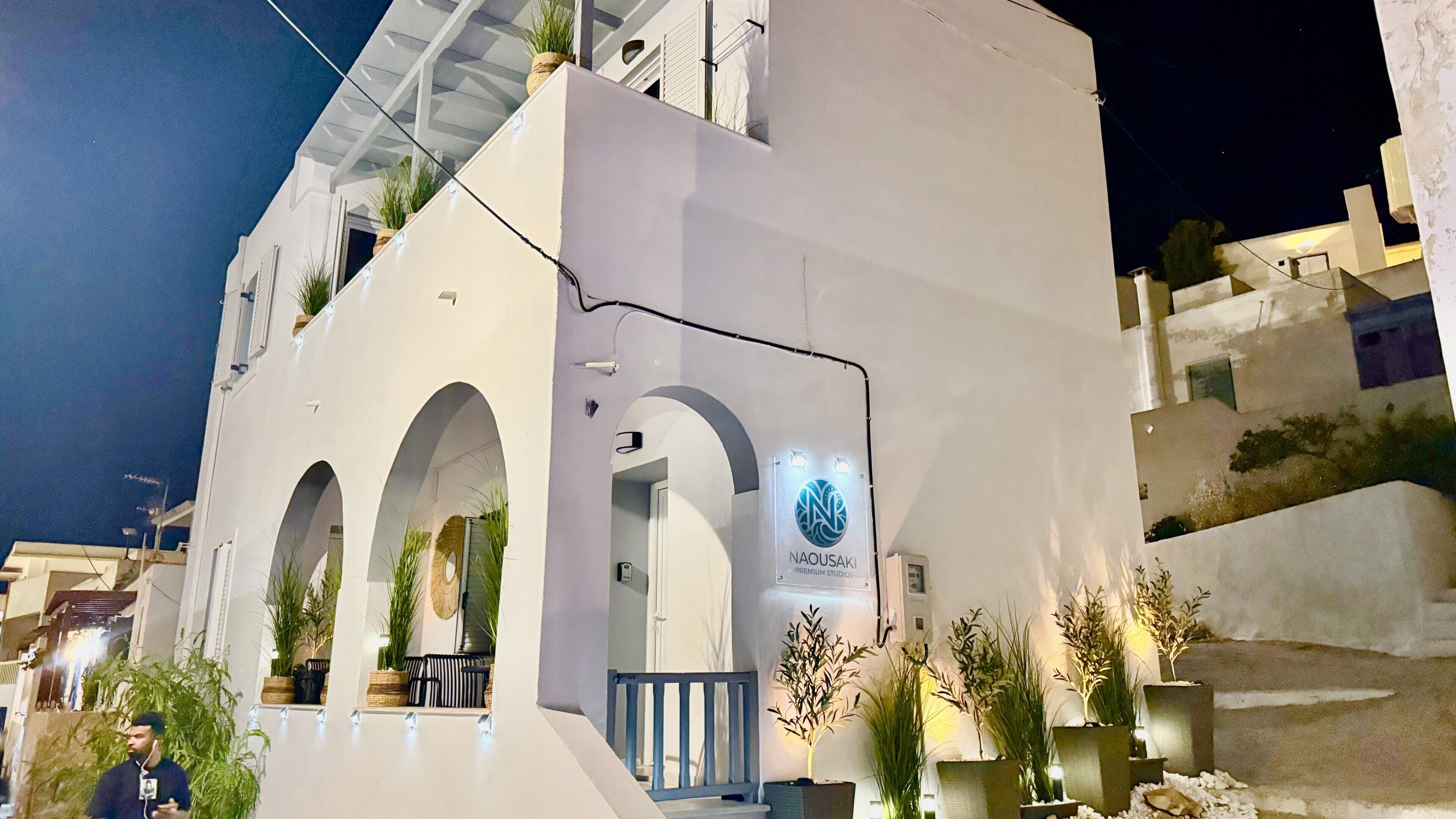 A building with a white facade, multiple arches, and a sign for 'NAOUSAKI PREMIUM STUDIOS.'