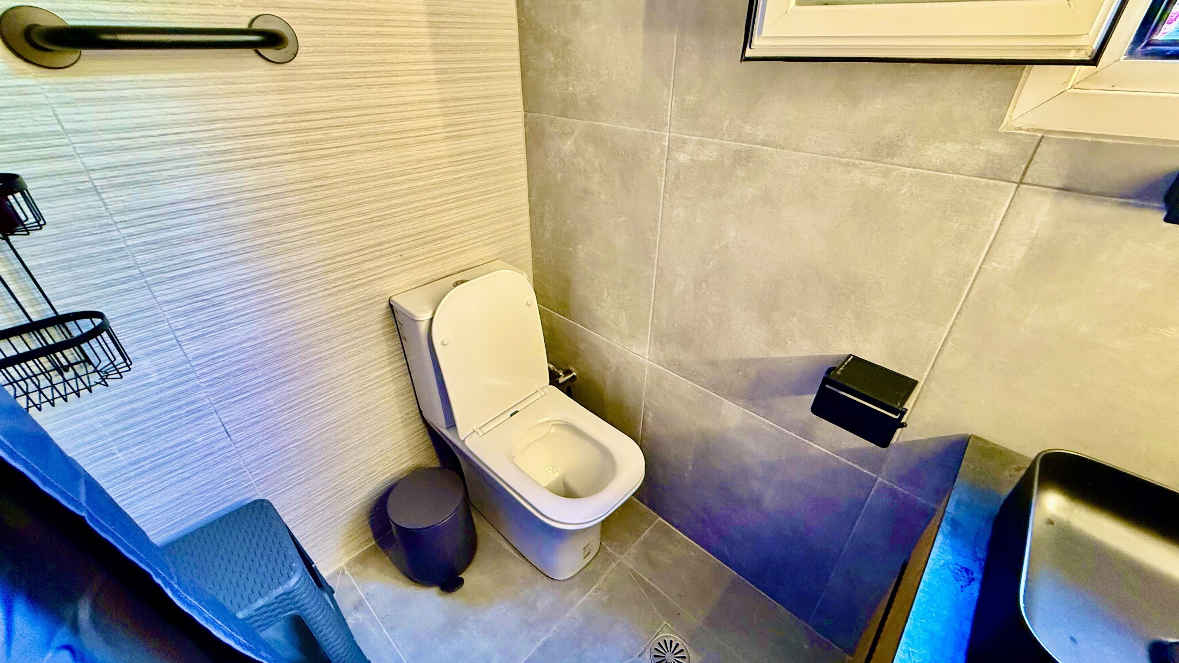 Ein modernes Badezimmer mit Toilette, Bidet, Mülleimer und Handtuchhalter.