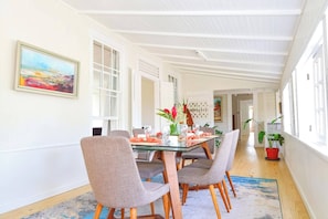 Ein Essbereich mit einem Glastisch, grau gepolsterten Stühlen und einer Vase mit Blumen.