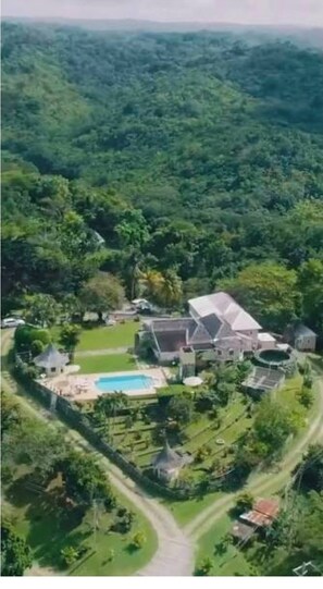 An aerial view of a large estate with a swimming pool, multiple buildings, and extensive greenery. - Pvt Villa Estate With Mtn Views Pool in Ocho Rios (Labyrinth)