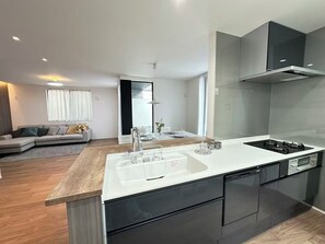 A modern kitchen with a central island, black cabinets, and a stainless steel range hood.