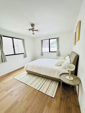 A bedroom with a large bed, two windows, a ceiling fan, and a bedside table with a lamp. - 130sqm Luxury New-build Terrace Home · 2 Parking · 5min Shinjuku & 7min Shibuya (Shibuya)