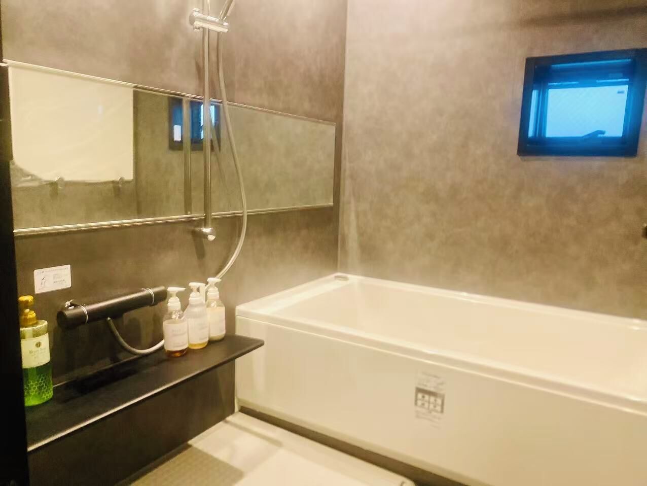 A modern bathroom with a bathtub, a mirror, and a shelf with toiletries.