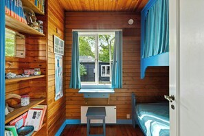 A cabin with a window, a desk, a bunk bed, and wooden shelves with various items. - Sea view and direct access to Sejerøbugten (Fårevejle)