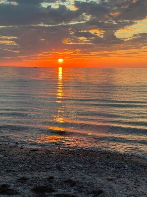 Ein Sonnenuntergang über einem ruhigen Meer mit einer felsigen Küste.