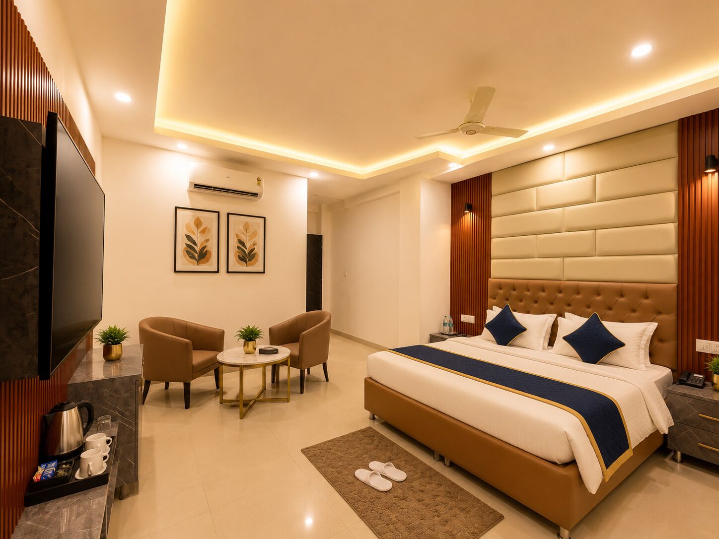 A modern hotel room with a large bed, a seating area with a table, and a television.