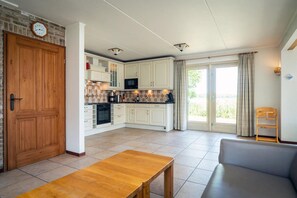 Eine geräumige Küche mit weißen Schränken, einer Holztür und einem Essbereich mit Tisch und Sofa.