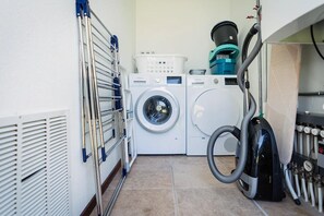 A laundry area with two washing machines, a drying rack, and a vacuum cleaner. - Texel Nature Villa with Sauna (De Koog)