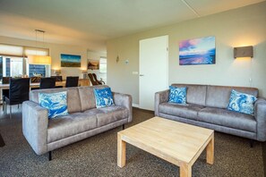 A living room with two sofas, a coffee table, and a dining area with chairs and a table. - 3-Bed Villa with Whirlpool (De Koog)