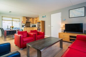 Una sala de estar moderna con sofás rojos, un comedor, una cocina y un televisor.