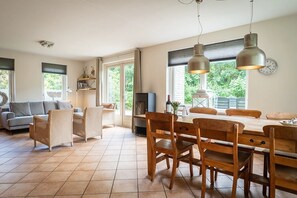 Uma sala ampla com sofá, cadeiras, mesa de jantar e lareira.
