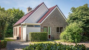 Ein zweistöckiges Haus mit rotem Ziegeldach, einer Ziegel-Fassade und einer weißen Garagentür.
