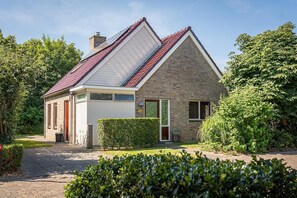 Ein zweistöckiges Haus mit rotem Ziegeldach, einer Ziegel-Fassade und einer weißen Garagentür.