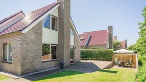 Ein zweistöckiges Haus mit Ziegelaußenwand, großen Fenstern und einem roten Ziegeldach.