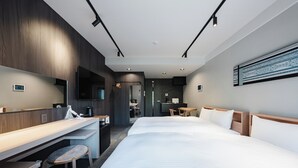 Ein Hotelzimmer mit einem großen Bett, einem Schreibtisch, einem Sessel, einem Fernseher und einem durch eine offene Tür einsehbaren Badezimmer.