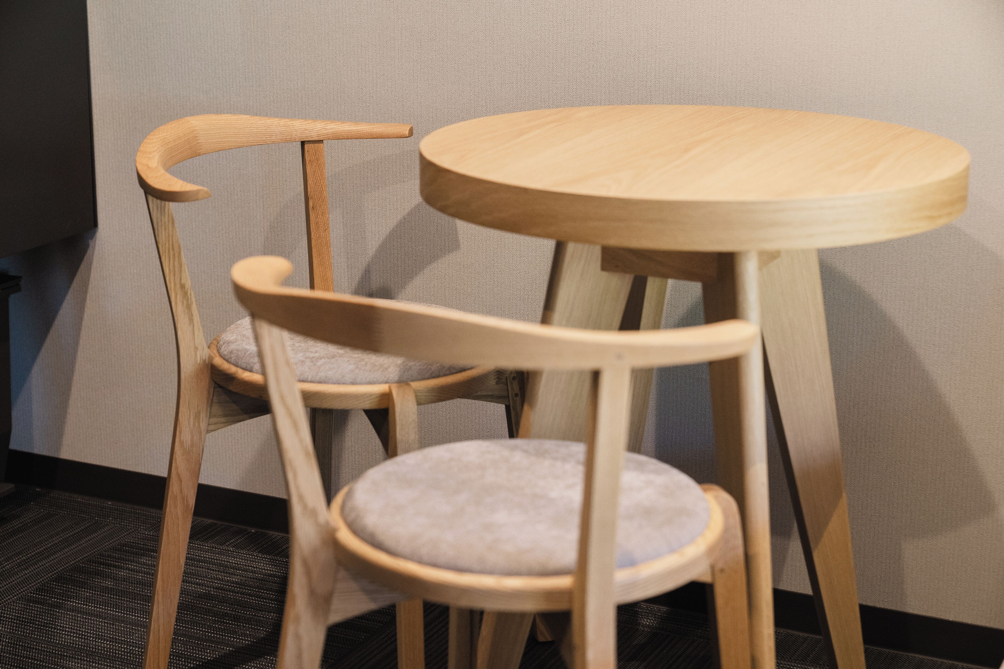A wooden chair with a cushioned seat and backrest, and a small round table with a wooden top.