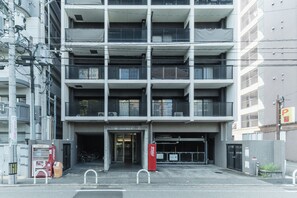 A multi-story building with a parking garage entrance, a Coca-Cola vending machine, and a red Coca-Cola sign. - TABIGOYA LIFE and TRIP TENJIN PARKSIDE (Fukuoka-shi)
