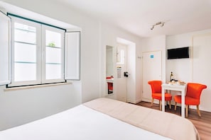 Ein Hotelzimmer mit einem Bett, einem Schreibtisch mit zwei Stühlen, einem Fernseher und einer Tür zu einem Badezimmer.