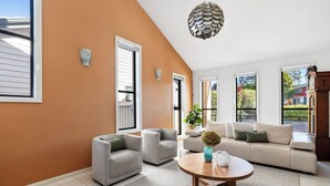 Een moderne woonkamer met een bank, twee fauteuils, een salontafel en een groot raam met uitzicht op het groen.
