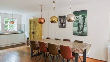 Een eetgedeelte met een tafel, stoelen en hangende lampen.