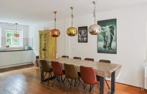 Een eetgedeelte met een tafel, stoelen en hangende lampen.