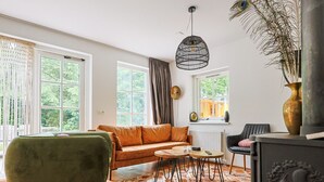 A living room with a sofa, a chair, a table, and a fireplace. - Luxury vacation home with a private sauna in Lunteren (Lunteren)