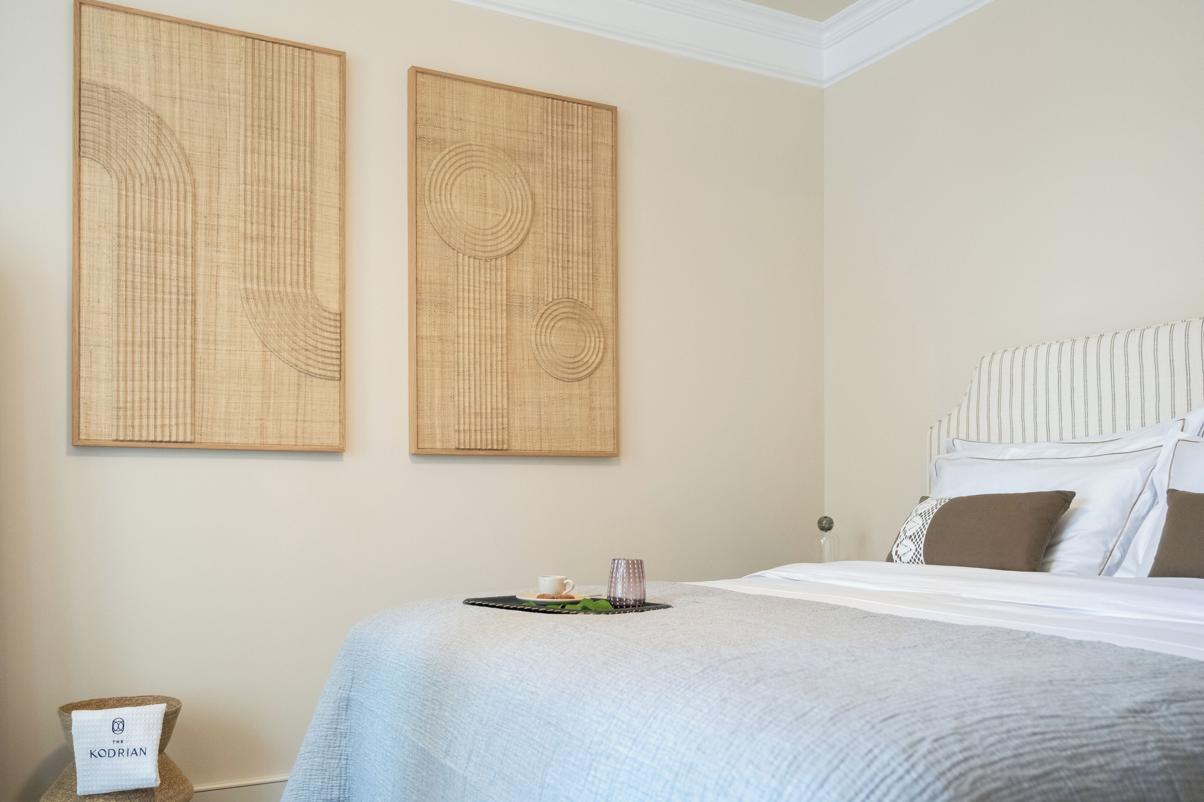 Ein Hotelzimmer mit einem Bett, einem Nachttisch, einem Wandbild und einem kleinen Tisch mit Tasse und Glas.